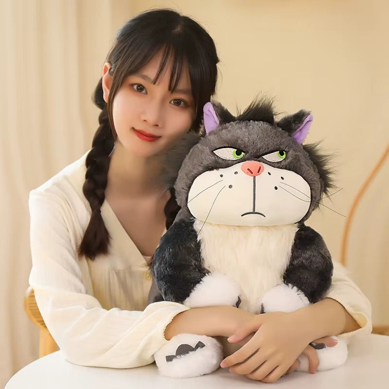 alt="Lucifer Bad Cat Plush Toy with grumpy face, soft black and white fur, and pink ears sitting on a couch – funny and collectible plushie"
