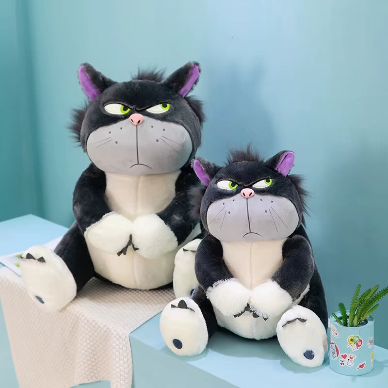 alt="Lucifer Bad Cat Plush Toy with grumpy face, soft black and white fur, and pink ears sitting on a couch – funny and collectible plushie"