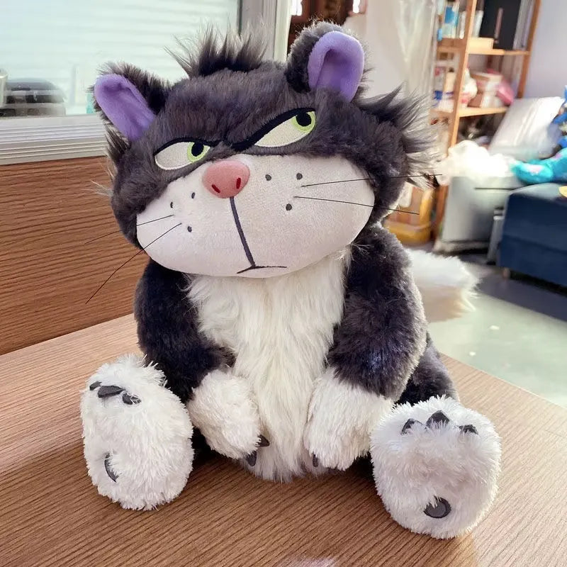 alt="Lucifer Bad Cat Plush Toy with grumpy face, soft black and white fur, and pink ears sitting on a couch – funny and collectible plushie"