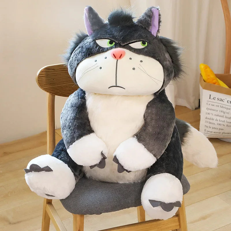 Lucifer Bad Cat Plush Toy with grumpy face, soft black and white fur, and pink ears sitting on a couch – funny and collectible plushie